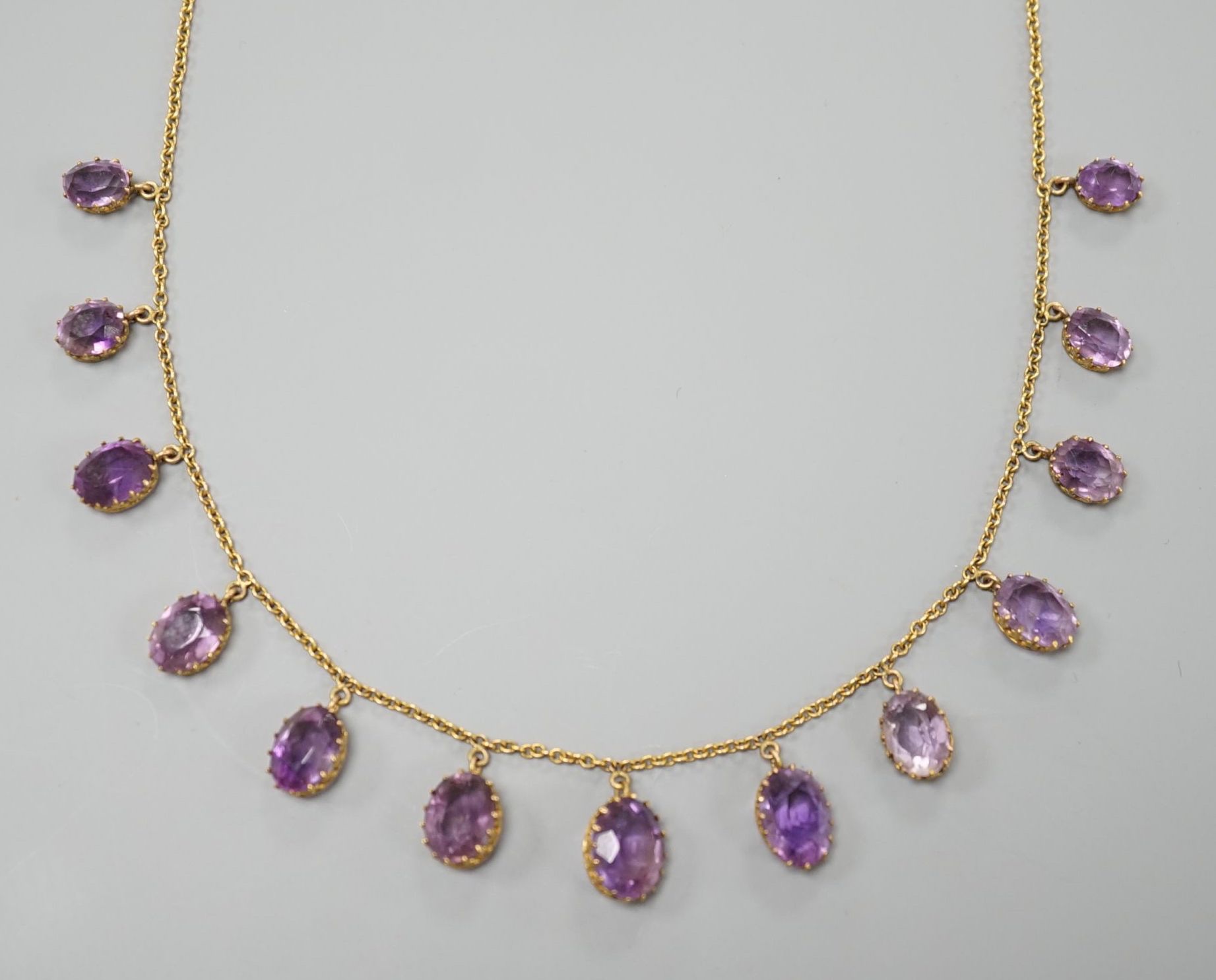 An early 20th century 9ct and graduated oval cut amethyst set drop fringe necklace, 45cm, gross weight 11.8 grams.